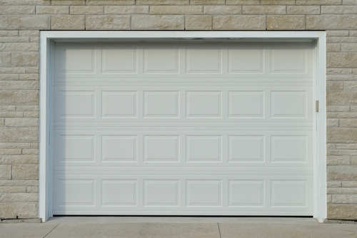 A white garage door framed by a brick wall, representing garage door installation in Miami.